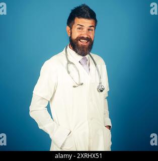 Portrait of smiling male doctor or physician in white medical coat with stethoscope in hospital. Bearded man in doctor uniform with stethoscope. Treat Stock Photo