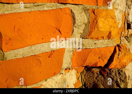 A textured brick wall features bright orange and gray elements under natural light conditions. Stock Photo
