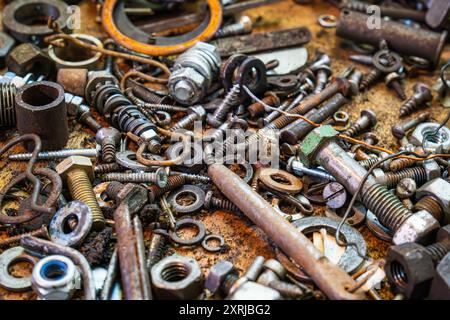 Detailed collection of various metal fasteners and hardware in a cluttered workshop setting during daylight hours Stock Photo