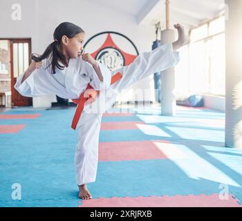 Martial arts, kick and student in studio for fitness, training and fight with orange belt, development and energy. Girl, kung fu and practice in dojo Stock Photo