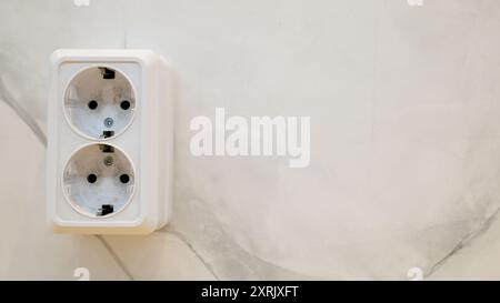 Close-up of a white double electrical outlet on a plain wall. European-style socket with round holes for plugs Stock Photo