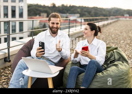 Young professionals working on rooftop with mobile devices Stock Photo