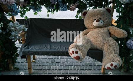 teddy bear on a bench under a flower arch Stock Photo