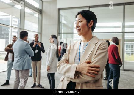 Confident professional woman in the office environment, engaging in networking and social interaction with colleagues, showcasing a modern workplace s Stock Photo