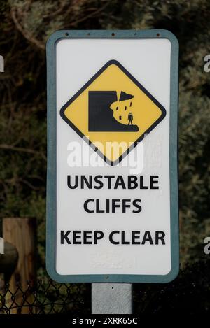 White unstable cliffs keep clear warning sign, featuring black and yellow icon of a crumbling cliff falling on a person Stock Photo