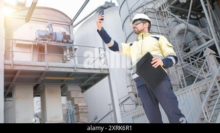 Engineer taking a photo with his mobile phone in a factory. Inspection concept in industry. Stock Photo