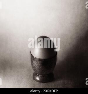 Egg in an antique egg cup, sepia image UK Stock Photo