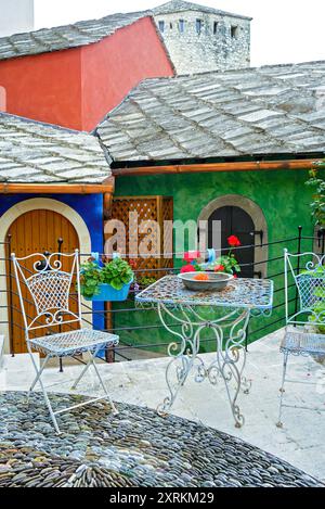 Cozy courtyard with a seating area in the Old Town of Mostar (Bosnia and Herzegovina): table and chairs against the backdrop of colorful walls Stock Photo