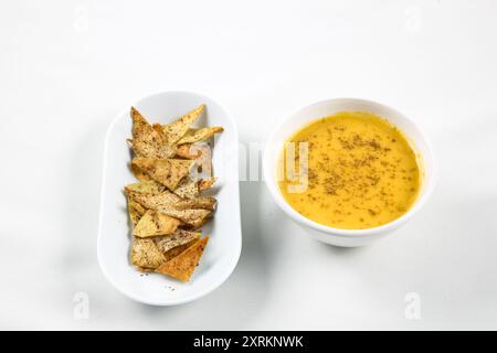 Pumpkin and carrot soup with cream and Pita bread chips on white background. bokeh shot. Stock Photo