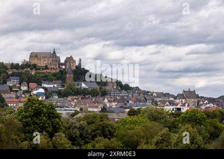 Marburg, Germany. 09th Aug, 2024. Marburg Castle, also known as Landgrave's Castle Marburg, rises above the town. View from the south with a view of the old town (upper town) with the Lutheran parish church (below the castle) and town hall (right). It originated as a castle in the 11th century and was converted into a residential palace by the Landgraves of Hesse in the 13th century. Since 1981, the castle has housed the Museum of Art History of the Philipps University of Marburg. Credit: Christian Lademann/dpa/Alamy Live News Stock Photo