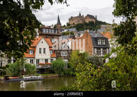 Marburg, Germany. 09th Aug, 2024. Marburg Castle, also known as Landgrave's Castle Marburg, rises above the town. View from the banks of the Lahn over houses in the southern quarter up to the old town (upper town). It originated as a castle in the 11th century and was converted into a residential palace by the Landgraves of Hesse in the 13th century. Since 1981, the castle has housed the Museum of Art History of the Philipps University of Marburg. Credit: Christian Lademann/dpa/Alamy Live News Stock Photo