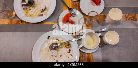 The leftover food and dirty empty dishes on the restaurant table. symbolize the end of lunch or dinner. Scraps left over after the party. Stock Photo