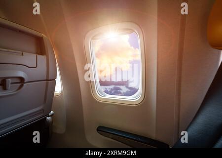 Aerial view from airplane window seat above sunset clouds in flight. Concept of traveling and cloud watching Stock Photo