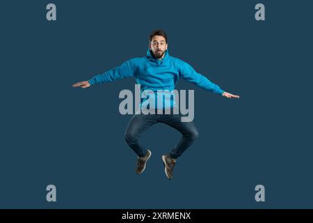 Young Man Jumping With Energy in Bright Blue Hoodie Stock Photo