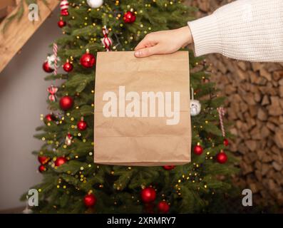 Christmas food delivery service. Hand holding paper bag mockup. Stock Photo