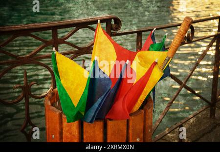 Annecy lake after rain. Broken colorful umbrella in garbage can. Retro aged grungy photo with scratches. Stock Photo