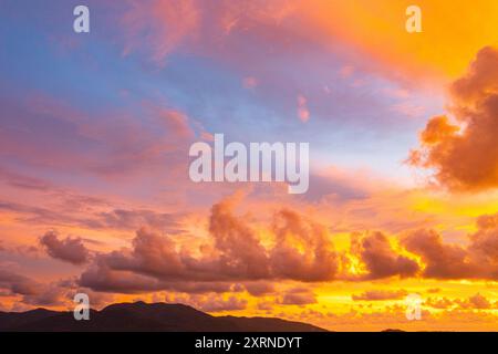 The sky is painted with hues of deep orange, red, and pink, gradually blending into shades of purple and blue. The clouds reflect these vibrant colors Stock Photo