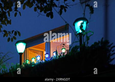 LED-Laternenlicht im Garten Kleine LED-Laternen mit einer Solarzelle an einem Haus, während das Sonnenlicht die Energie für das nächtliche Licht speichert. *** LED lantern light in the garden Small LED lanterns with a solar cell on a house, while the sunlight stores the energy for the night light Stock Photo