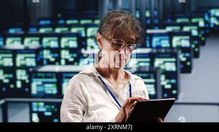 Skilled computer scientist in data center equipped to handle complex computing requirements, doing regular upgrades to server clusters, increasing processing power to prevent malfunctions Stock Photo