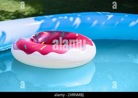 Inflatable swimming ring donut in an inflatable pool with blue water. Summer vacation. Stock Photo