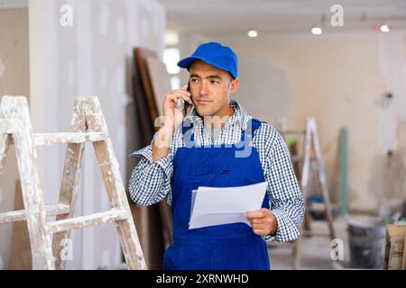 Young foreman with documents in his hands is talking on a mobile phone Stock Photo