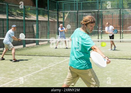Adult men playing padel against two men Stock Photo