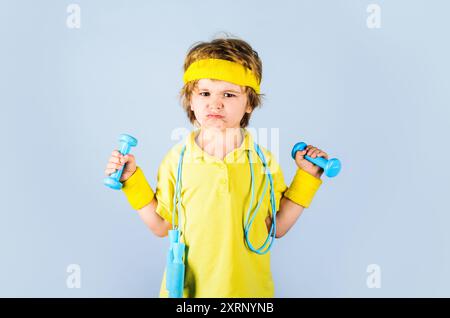 Sporty boy with jumping rope and dumbbells. Childhood activity. Healthy lifestyle. Kid boy in sportswear with skipping rope and dumbbells. Gym workout Stock Photo