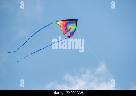 Rainbow tie dye kite flying in the sky Stock Photo