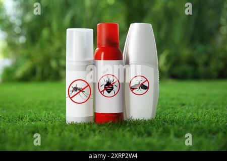 Different insect repellents in spray bottles on green grass outdoors Stock Photo