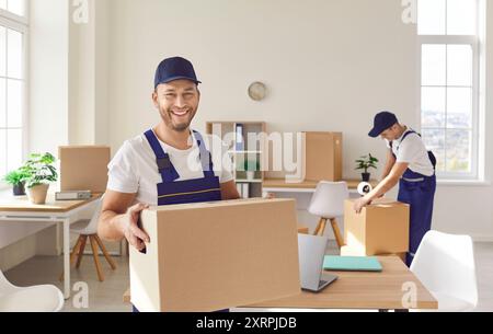 Happy movers male professional team in overalls loading, packing and unloading Stock Photo