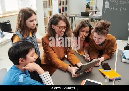 Smiling Female Teacher using Tablet with Kids Stock Photo