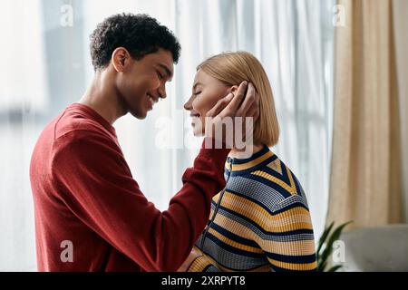A happy, multicultural couple enjoys a tender moment together in their modern apartment. Stock Photo