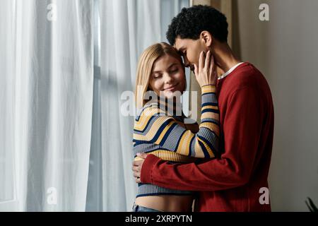 A happy interracial couple enjoys a tender moment together in their modern apartment, showcasing the beauty of diverse relationships. Stock Photo