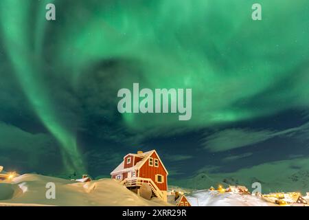 Green northern lights, aurora borealis over a typical greenlandic red house, Tasiilaq, East Greenland, Greenland Stock Photo