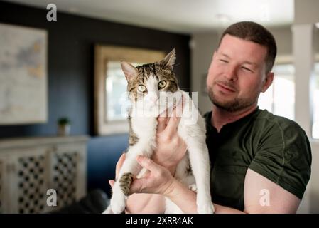 Man holding cat in home Stock Photo