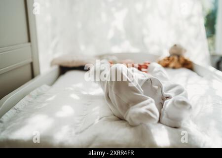 Newborn baby lying down at home on bed view of feet dressed in white Stock Photo