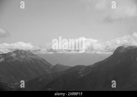 Paraglider flying over Alps mountains. Annecy lake area (Haute-Savoie, France). Aged photo. Black and white. Stock Photo