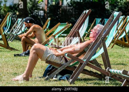 London, UK. 12th Aug, 2024. Sunbathing while taking a break in on the deckchairs in Green Park - Another mini late summer autumn heatwave, leads to sunny weather and brings people outside at lunchtime in London. Credit: Guy Bell/Alamy Live News Stock Photo