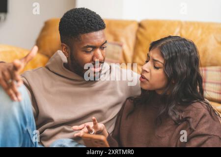man and woman hugging, sitting at home, young couple having fun together, looking at phone, watching videos, chatting or shopping online, sitting on s Stock Photo