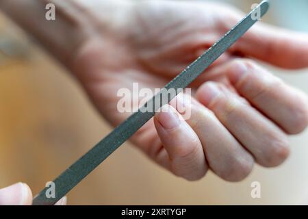 Close-up view of a skilled manicurist shaping and filing a woman's nails with accuracy and care using a nail file tool, ensuring a well-groomed and po Stock Photo