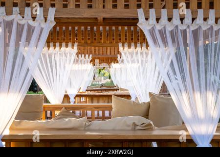 Sunbeds (empty) at Atzaro ibiza with white lacey curtains in sunlight Stock Photo
