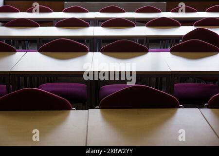 Inside a classroom or lecture room with empty rows of chairs set against tables. Stock Photo