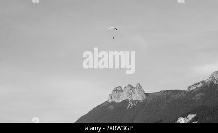 Paraglider flying over the mountains of Savoy at Annecy Lake (France). Power of nature idea. Aged photo. Black and white. Stock Photo