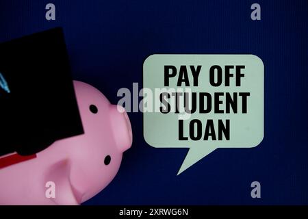 Pay off student loan text on speech bubble with piggy bank and graduation cap top view on navy blue background Stock Photo