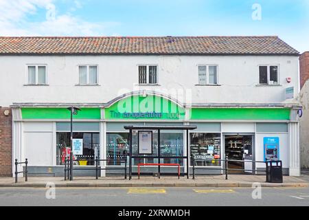 The Food Co-operative shoppers store sign facade & shop windows beside bus stop shelter hole in wall cash machine Sedgefield County Durham England UK Stock Photo