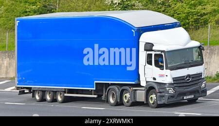 White Tesco Supermarket streamlined prime mover Mercedes hgv lorry truck combined blue hard body shaped semi trailer on M25 motorway Essex England UK Stock Photo