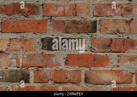 A brick wall with a few missing bricks. The wall is brown and red in color. The wall is old and has a rough texture Stock Photo