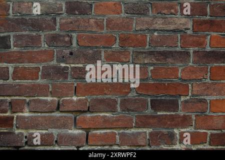 A brick wall with a few missing bricks. The wall is brown and has a rough texture. The missing bricks create a sense of imperfection and give the wall Stock Photo