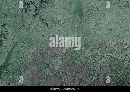 The wall is covered in green paint and has a lot of cracks and holes. The paint is peeling off and the wall looks old and worn out Stock Photo