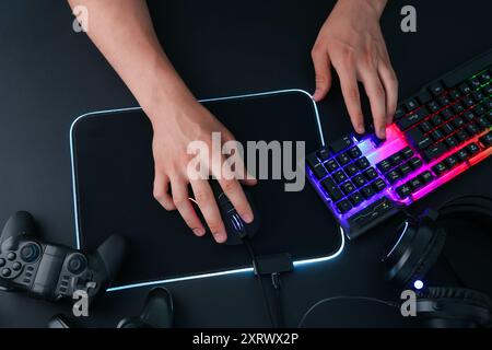 Gamer using modern wired computer mouse at black table, top view Stock Photo